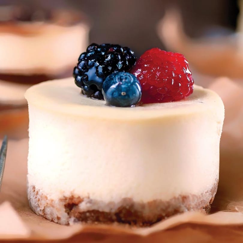 A mini cheesecake from Crumble & Whisk, topped with a blackberry, a blueberry, and a raspberry.