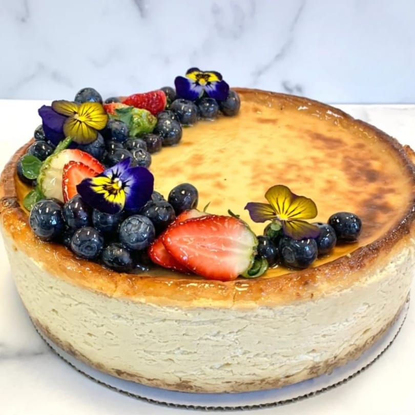 Crumble & Whisk cheesecake topped with fresh blueberries, strawberries, and edible pansy flowers.