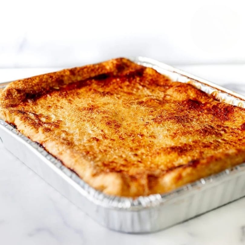 A golden-brown Crumble & Whisk dessert, possibly a cobbler or crumble, in a foil baking pan.